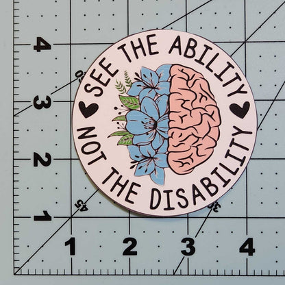 Circular sticker with brain and flower design on a cutting mat with ruler