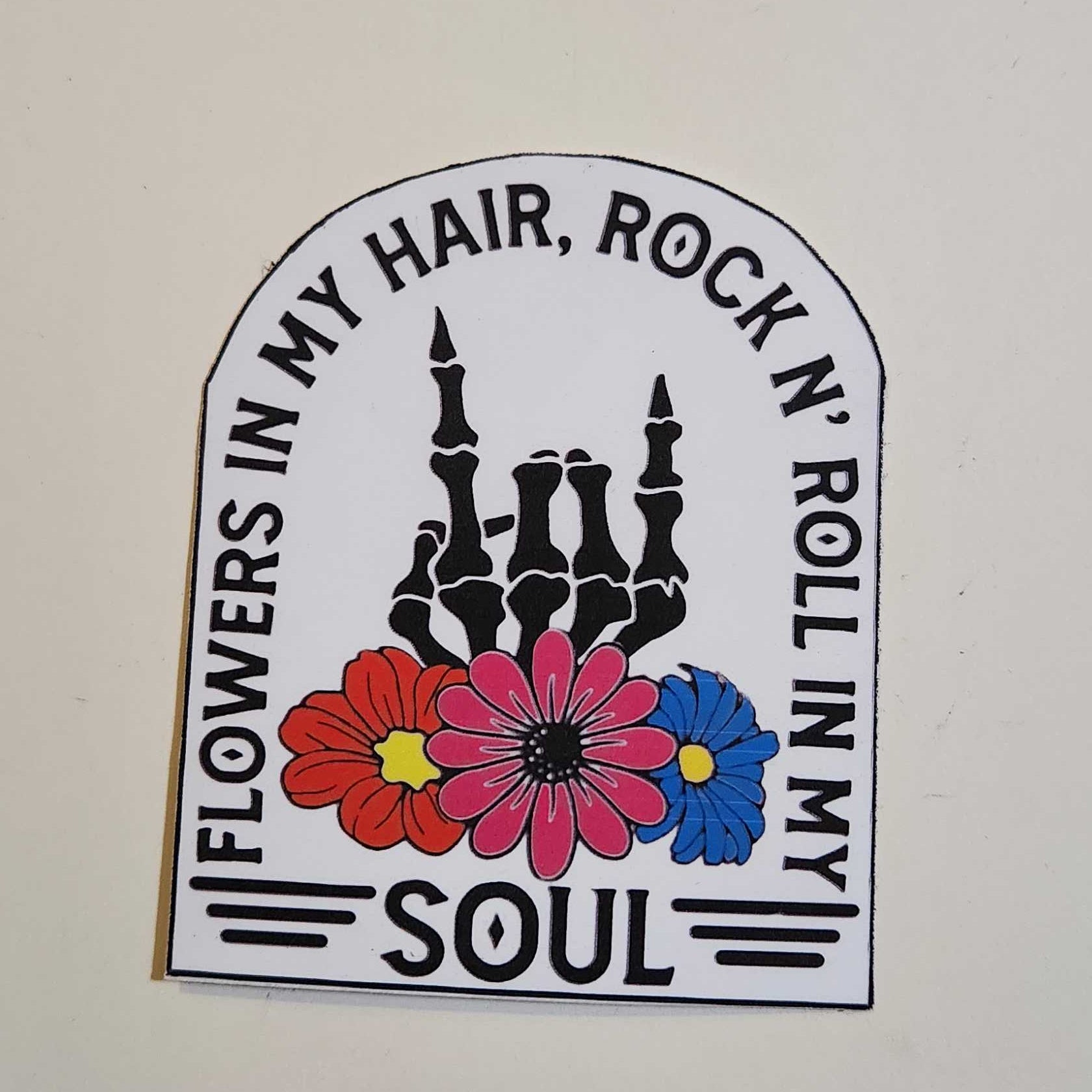 Sticker with skeleton, flowers, and text on a white background