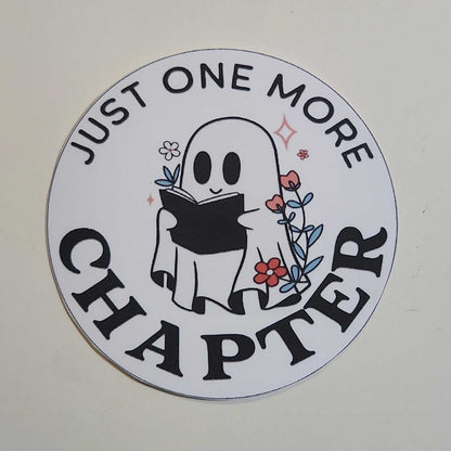 Circular sticker with a ghost design and text 'Just One More Chapter' on a white background