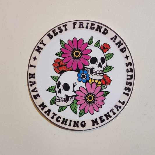 Circular sticker with floral and skull design on a plain background