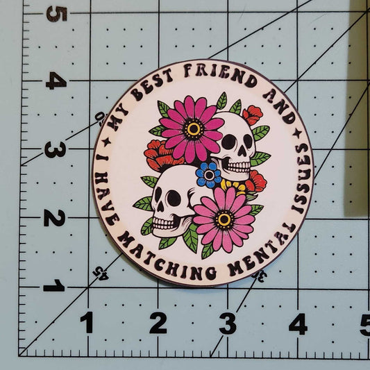 Circular sticker with floral skull design on a cutting mat with ruler