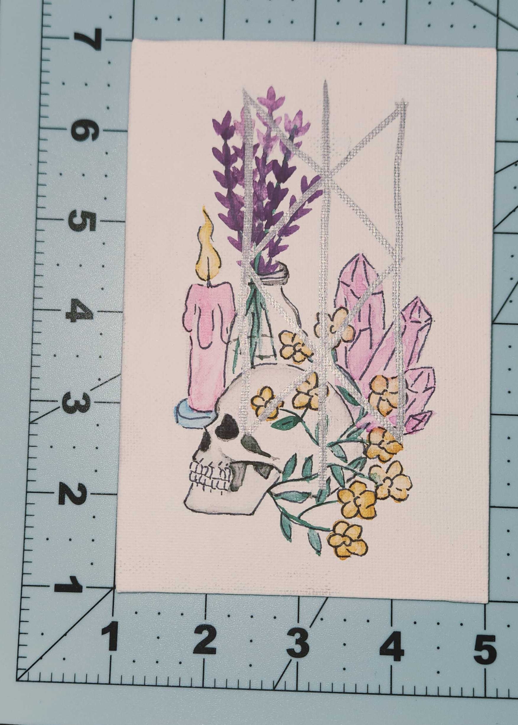 Illustration of a skull with flowers and candles on a cutting mat with ruler