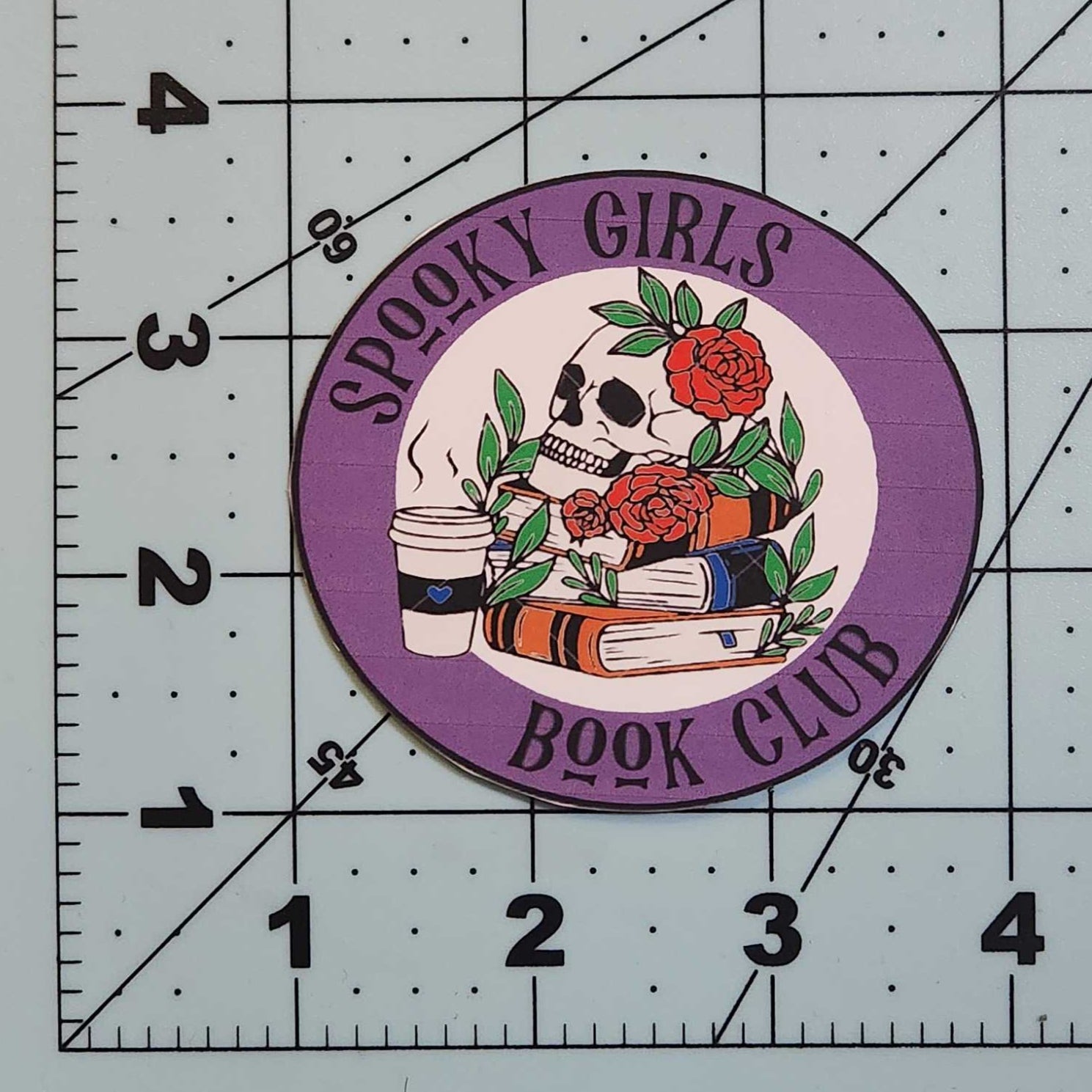 Circular patch with text and graphics on a cutting mat with measurements.