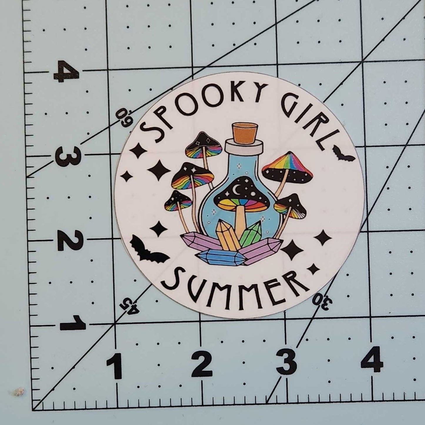 Sticker with 'Spooky Girl Summer' design on a cutting mat
