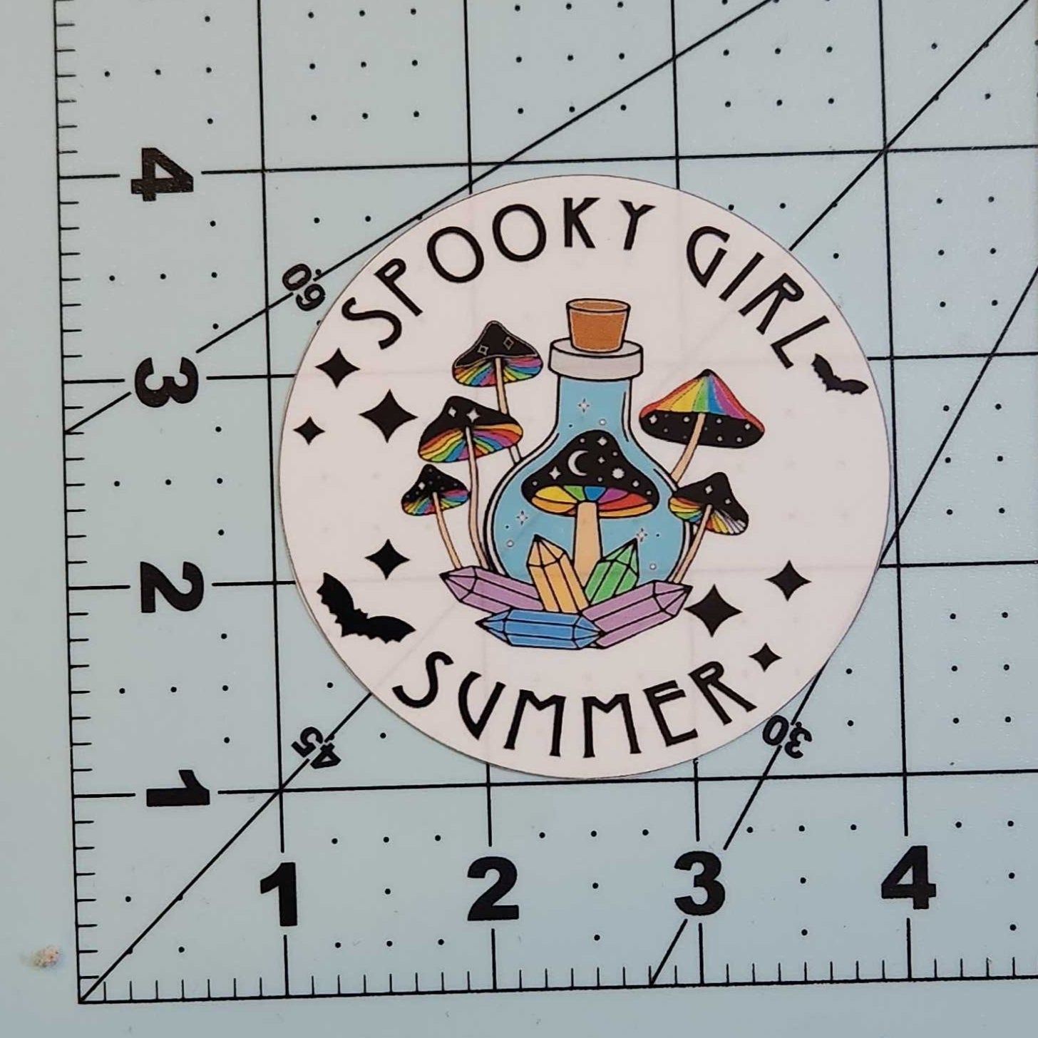 Sticker with 'Spooky Girl Summer' design on a cutting mat