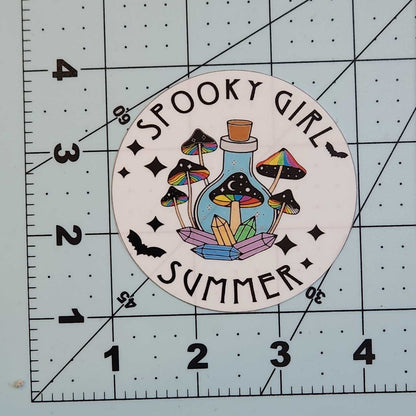 Sticker with 'Spooky Girl Summer' design on a cutting mat