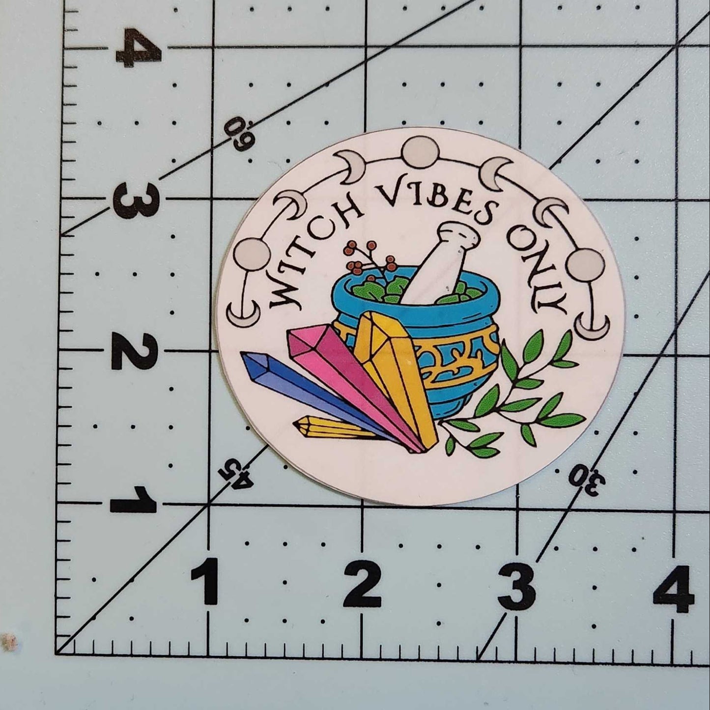 Circular sticker with 'Witch Vibes Only' text and colorful design on a ruler.