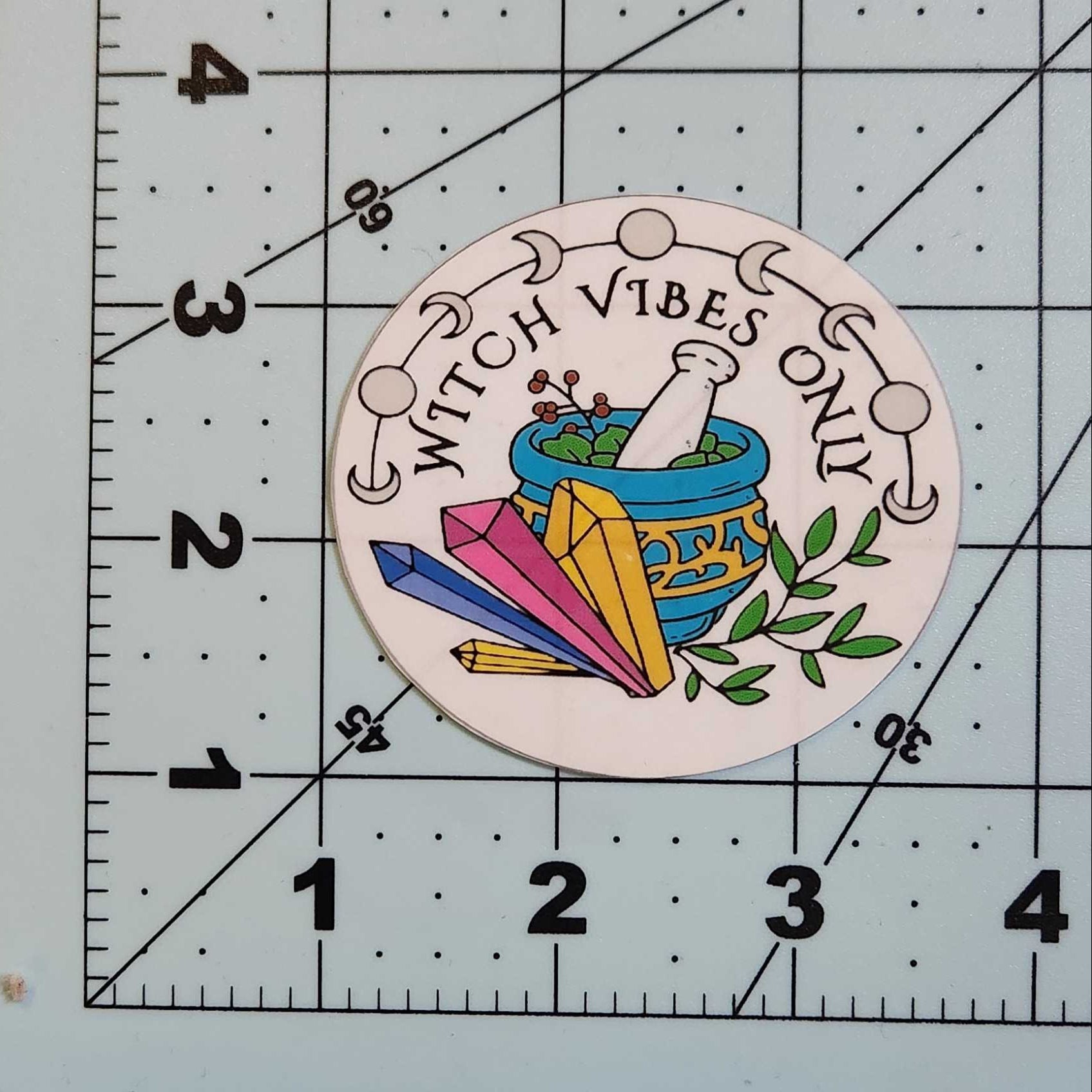 Circular sticker with 'Witch Vibes Only' text and colorful design on a ruler.