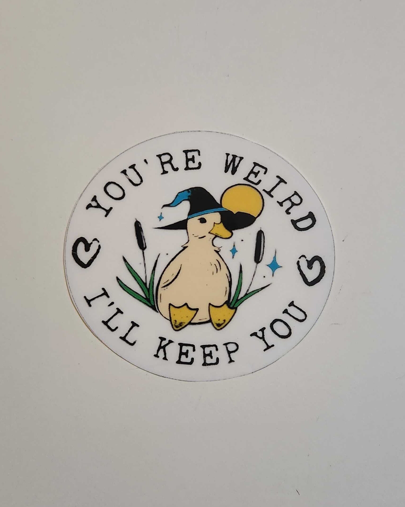 Circular sticker with a duckling design and text on a white background 